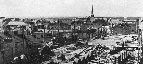 Mustavalkoinen kuva Eduskuntatalon katolta talon rakennusvaiheessa. Maisemat näkyvät kauas.