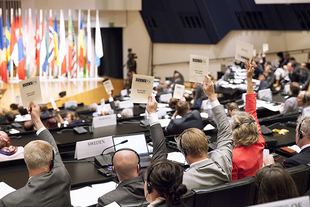 Kansanedustajat äänestävät kättä nostamalla Etyjin parlamentaarisen yleiskokouksen istunnossa.