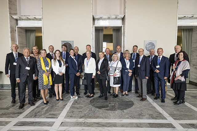 Kunniakonsulit seisovat ryhmäkuvassa Eduskuntatalon Valtiosalissa.