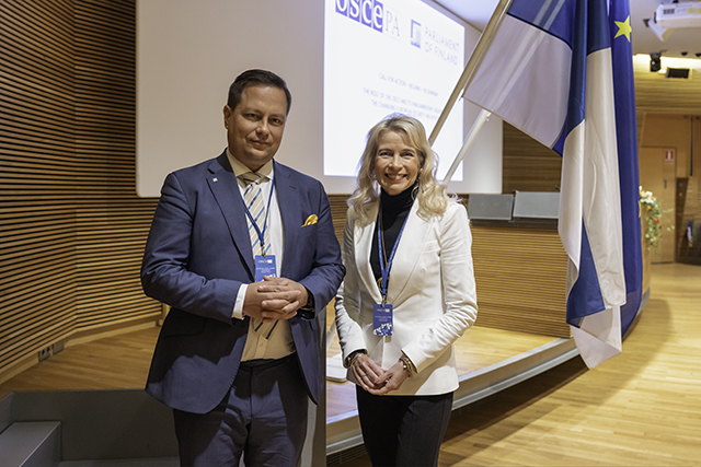 Vilhelm Junnila ja Pia Kauma Pikkuparlamentin auditoriossa, taustallaan Suomen ja EU:n liput.