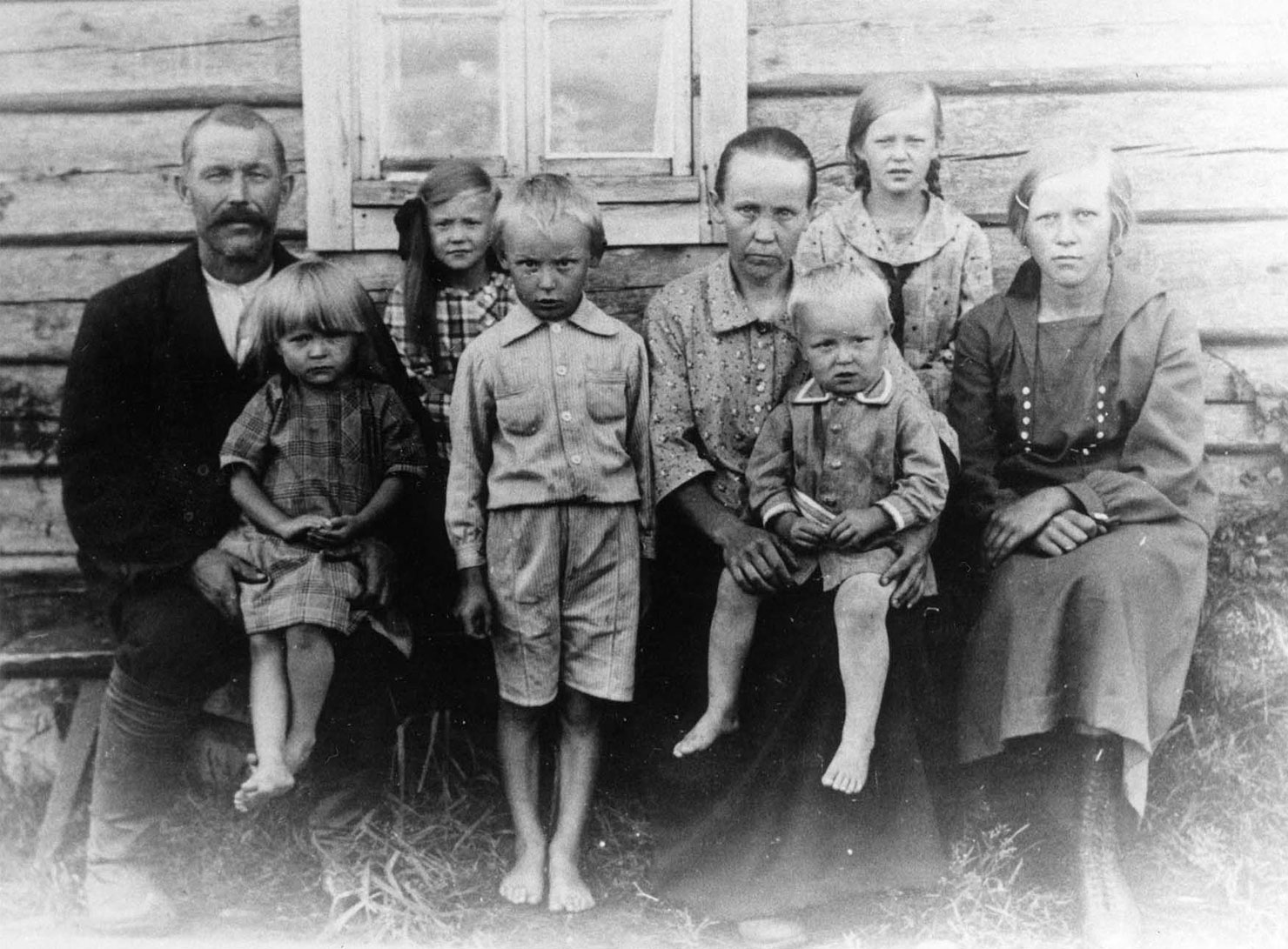 Valokuvassa torppariperhe, vanhemmat ja 6 lasta kotinsa edustalla kuvattuna kesäaikaan.